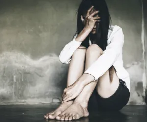 Femme recroquevillée assise contre un mur, symbolisant les expériences émotionnelles difficiles récentes ou anciennes