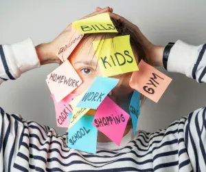 Femme submergée par la charge mentale, postit collés sur le visage représentant stress, enfants et travail