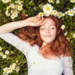 Femme allongée dans l’herbe avec une couronne de fleurs, représentant une libération énergétique douce sans reviviscence traumatique