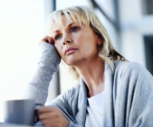 Femme pensive assise avec une tasse de café, exprimant une perte d’identité et une fatigue émotionnelle