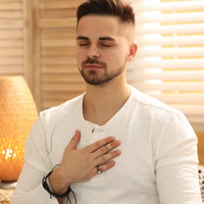 Homme méditant avec la main sur le cœur, symbole de recentrage et guérison énergétique en séance neuroénergétique