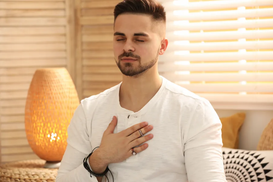 Homme méditant avec la main sur le cœur, symbole de recentrage et guérison énergétique en séance neuroénergétique