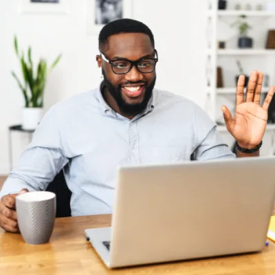 Homme souriant en visioconférence, participant à une séance de coaching neuroénergétique à distance