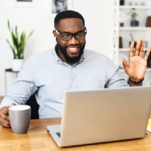 Homme souriant en visioconférence, participant à une séance de coaching neuroénergétique à distance