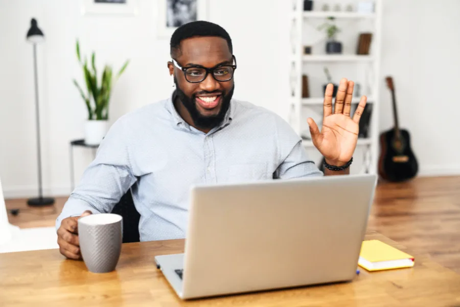 Homme souriant en visioconférence, participant à une séance de coaching neuroénergétique à distance