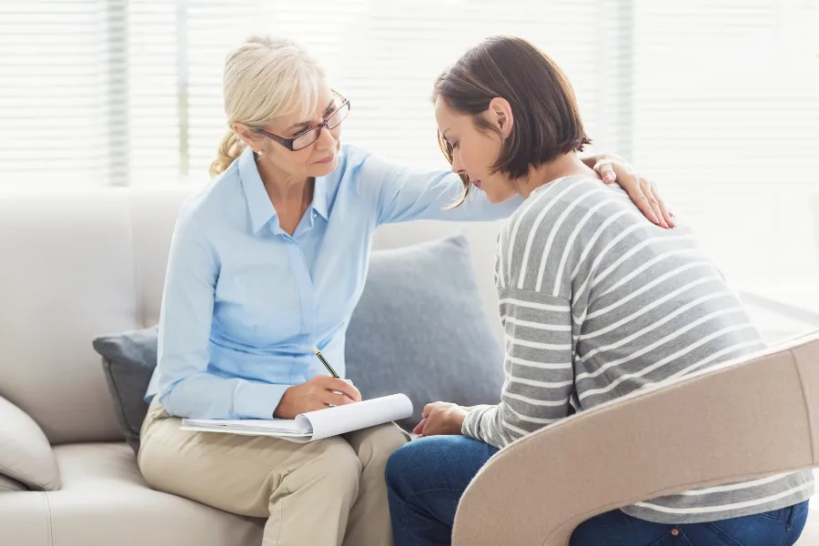 Coach bienveillante qui accompagne une maman en détresse face aux difficultés de son enfant neuroatypique