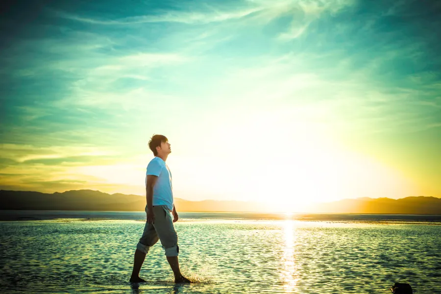 Jeune homme sur la plage réfléchissant à sa vie avec positivité après une séance neuroénergétique avec Nadège Augereau