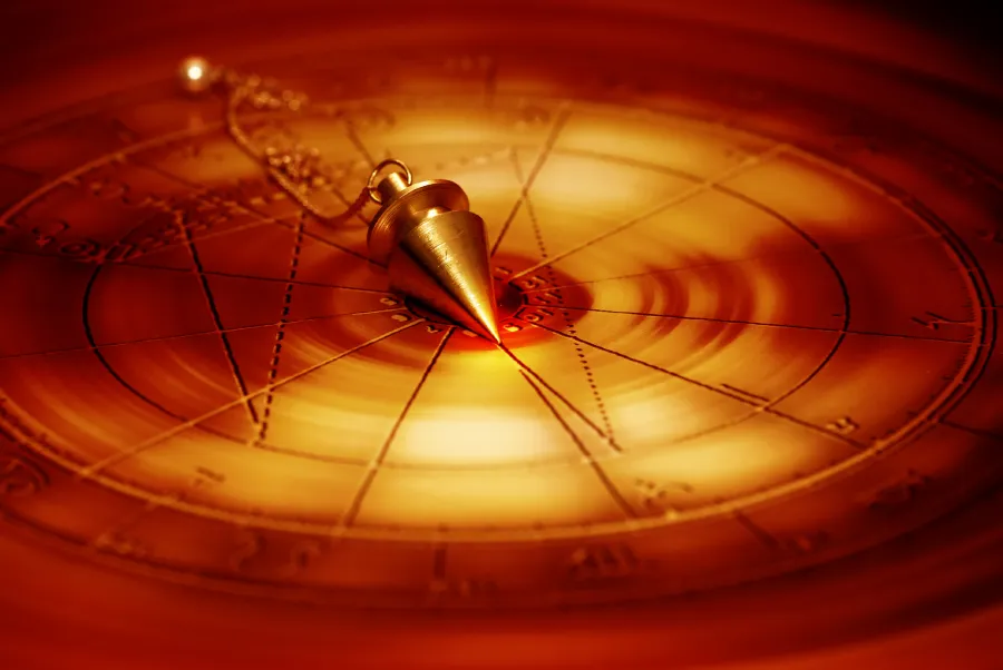 Une planche de radiesthésie couleur or avec un pendule